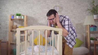tired young father and crying child ,puts on headphones