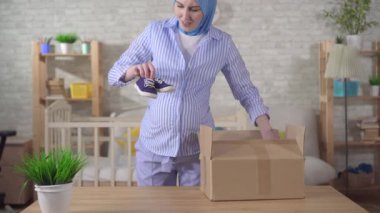tesettürlü genç hamile kadın bebek ayakkabılarını açıyor.
