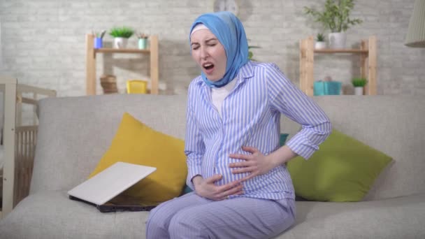 Een jonge zwangere moslim vrouw in hijab ervaringen prenatale contracties — Stockvideo