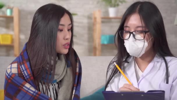 Arzt in medizinischer Schutzmaske interviewt kranke Asiatin aus nächster Nähe — Stockvideo