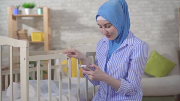 Muslim young woman is a mother by the bed in the nursery — Stockvideo