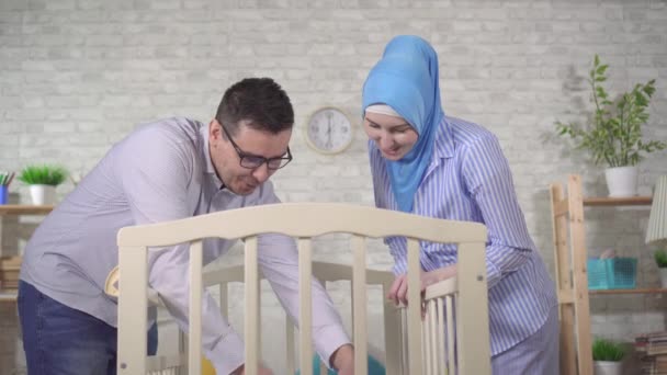 Portrait of a happy young Muslim family with a newborn baby at the childrens bed — Stock Video