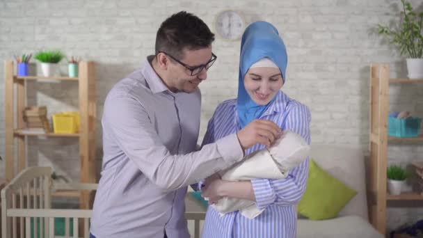 Yeni doğmuş bebeği olan mutlu, genç Müslüman bir aile kameraya bakıp gülümsüyor. — Stok video
