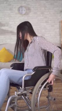 Oturma odasında tekerlekli sandalyedeki Asyalı engelli bir kadının portresi.