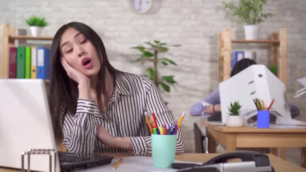 İki genç Asyalı ofis çalışanı iş yerinde uyuyorlar ve telefondan uyanıyorlar. — Stok video