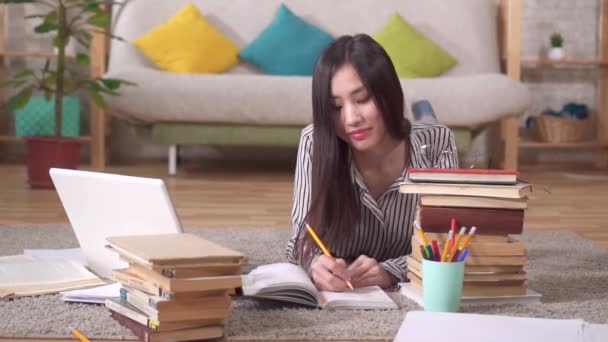 Retrato de una hermosa estudiante asiática con libros mirando a la cámara — Vídeos de Stock