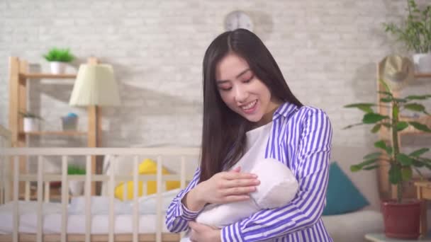 Egy pozitív, mosolygós ázsiai anya portréja egy babával a karjában. — Stock videók