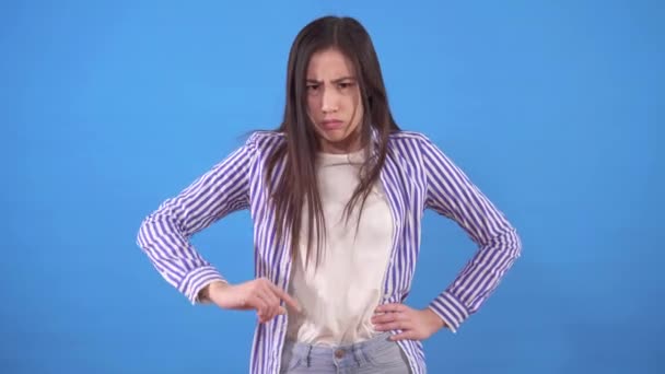Genç somurtkan Asyalı kadın mavi bir arka planda duruyor ve parmağını inkar ediyor. — Stok video