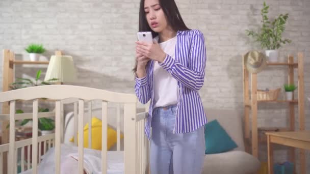 Волнуется молодая азиатская мама зовет на помощь по телефону — стоковое видео