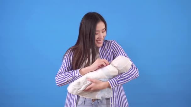 Young asian mom with baby on blue background — Stock Video
