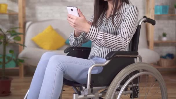 車椅子の若いアジア系障害者の女性はスマートフォンを使い — ストック動画