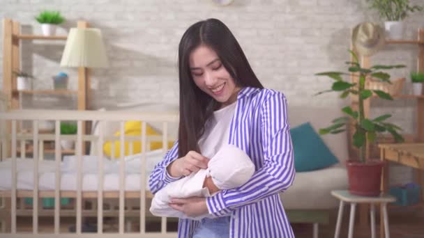 Retrato de una joven madre asiática positiva con un bebé en sus brazos — Vídeo de stock