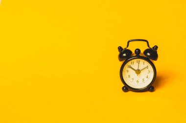 Sarı arka planda klasik çalar saat. Yuvarlak tuşlu klasik saat. Boşluğu kopyala