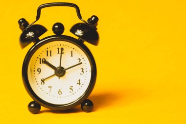 Sarı arka planda klasik çalar saat. Yuvarlak tuşlu klasik saat. Boşluğu kopyala