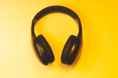 Sarı arka planda siyah kulaklıklar. kablosuz kulaklıklar