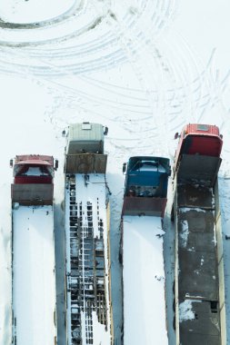 Kamyon karların altında. Kardan sonra karla kaplı bir kamyon. Uzun kamyonlar bir sıra üstte duruyor. Ulaşım konsepti. Kar kaplı araçlar. Kopyalama alanı olan hava görünümü