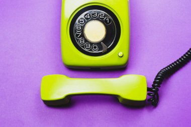 Cep telefonlu klasik bir telefon. Mor arka planda izole edilmiş telefon ahizesi olan klasik yeşil bir telefon. Eski iletişim teknolojisi. Boşluğu kopyala