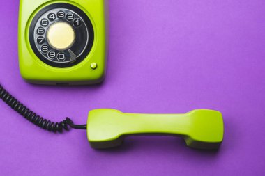 Cep telefonlu klasik bir telefon. Mor arka planda izole edilmiş telefon ahizesi olan klasik yeşil bir telefon. Eski iletişim teknolojisi. Boşluğu kopyala