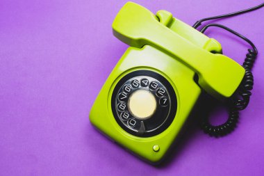 Cep telefonlu klasik bir telefon. Mor arka planda izole edilmiş telefon ahizesi olan klasik yeşil bir telefon. Eski iletişim teknolojisi. Boşluğu kopyala