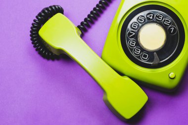 Cep telefonlu klasik bir telefon. Mor arka planda izole edilmiş telefon ahizesi olan klasik yeşil bir telefon. Eski iletişim teknolojisi. Boşluğu kopyala