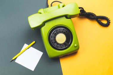 Cep telefonlu klasik bir telefon. Üzerinde bir not olan kalem. Ofis geçmişi. Telefon ahizesi olan klasik yeşil bir telefon. Eski iletişim teknolojisi. Boşluğu kopyala