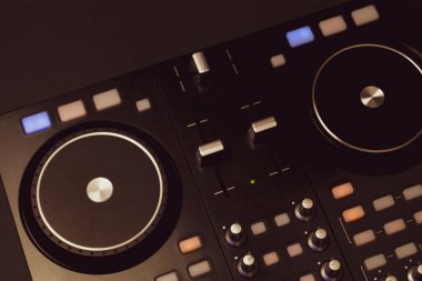 Düğmeleri ve sürgüleri olan DJ ses karıştırıcı kontrolörü. ses karıştırma güvertesi ile pikaplar karanlıkta aydınlatma kontrolleri ile