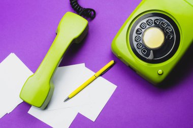 Cep telefonlu klasik bir telefon. Üzerinde bir not olan kalem. Ofis geçmişi. Telefon ahizesi olan klasik yeşil bir telefon. Eski iletişim teknolojisi. Boşluğu kopyala