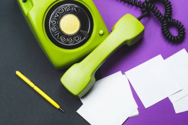 Cep telefonlu klasik bir telefon. Üzerinde bir not olan kalem. Ofis geçmişi. Telefon ahizesi olan klasik yeşil bir telefon. Eski iletişim teknolojisi. Boşluğu kopyala