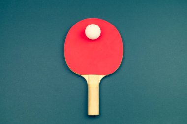 Kırmızı masa tenisi raketi ve renkli arka planda izole edilmiş bir top. Masa tenisi için spor malzemeleri. Boşluğu kopyala