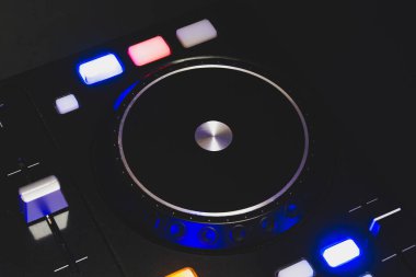 Düğmeleri ve sürgüleri olan DJ ses karıştırıcı kontrolörü. ses karıştırma güvertesi ile pikaplar karanlıkta aydınlatma kontrolleri ile