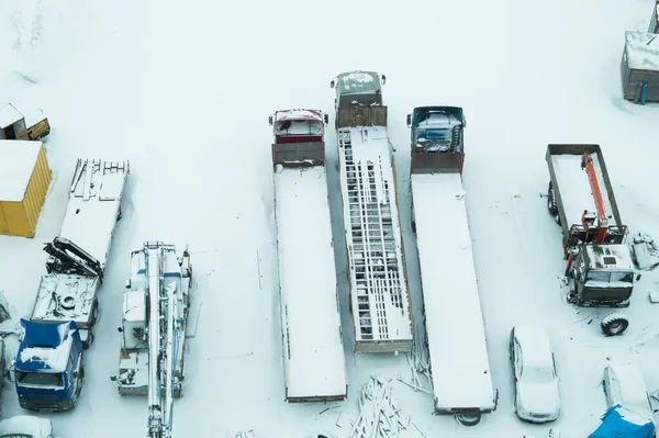 Truck under the snow. lorry covered with snow after snowfall. long trucks stand in a row top view. transportation concept. snow covered vehicles. aerial view with copy space