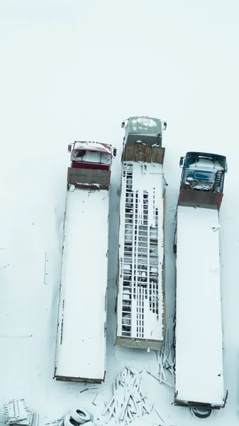 Truck under the snow. lorry covered with snow after snowfall. long trucks stand in a row top view. transportation concept. snow covered vehicles. aerial view with copy space