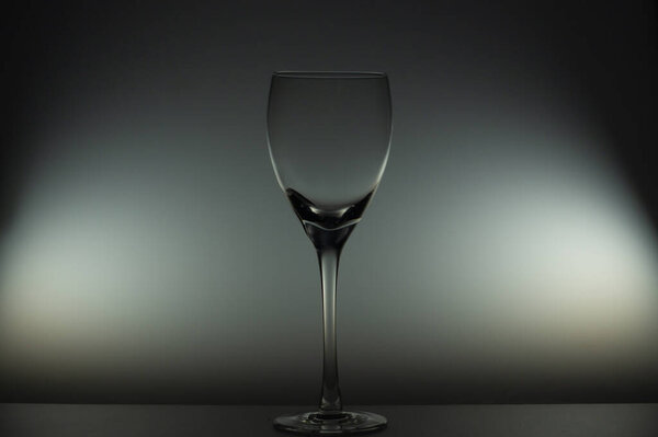 Empty wine glass stands on the table in the dark