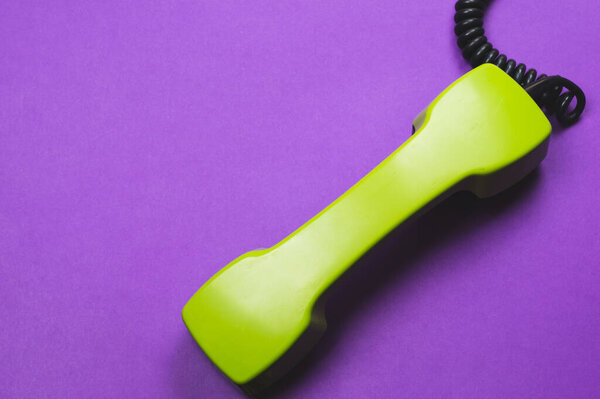 Vintage green telephone handset. phone receiver isolated on purple background. old communication technology. copy space