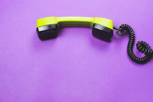 Klasik yeşil telefon ahizesi. Mor arka planda izole edilmiş bir telefon alıcısı. Eski iletişim teknolojisi. Boşluğu kopyala