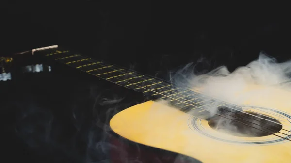Guitar in smoke close up. acoustic musical instrument. strings on the guitar neck