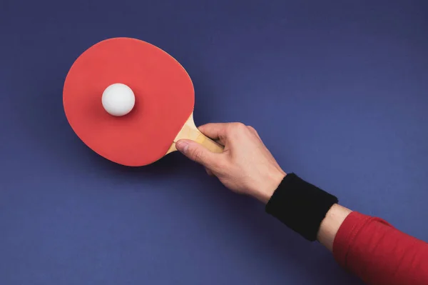 Red table tennis racket in hand. hitting the ball. sport equipment for ping pong. copy space