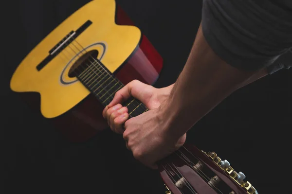 Hands holds acoustic guitar. musical instrument on black background