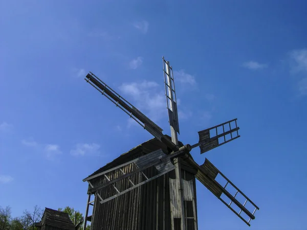 Staré dřevěné větrné mlýny. Větrný mlýn s čerstvou trávou a jasné modrá obloha v letním dni. Národnostní muzeum Pirogovo, Kyjev, Ukrajina — Stock fotografie