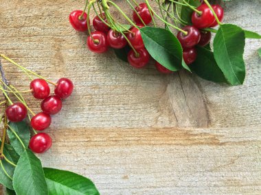 Ahşap zemin üzerinde yaprakları olan taze kirazlar..