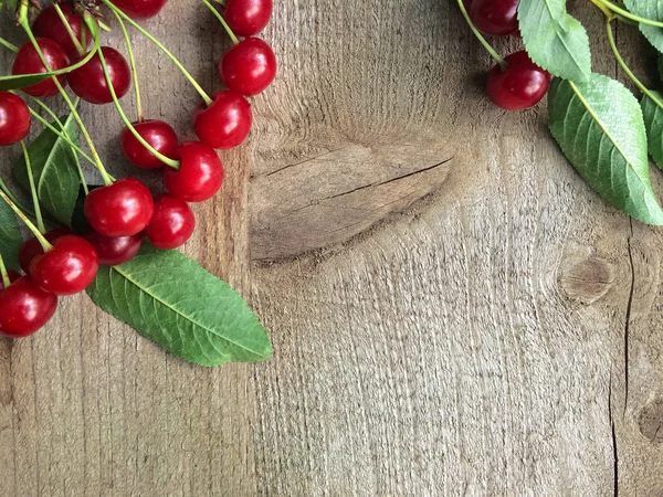 Fresh sweet cherries with leaves on wooden background, top view. — Stock Photo, Image