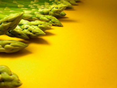 Çiğ kuşkonmaz. Sarı arka planda taze yeşil kuşkonmaz..