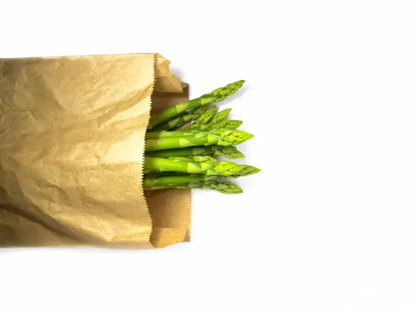 Surowe szparagi w papierowej torbie. Świeże zielone szparagi na białym tle — Zdjęcie stockowe