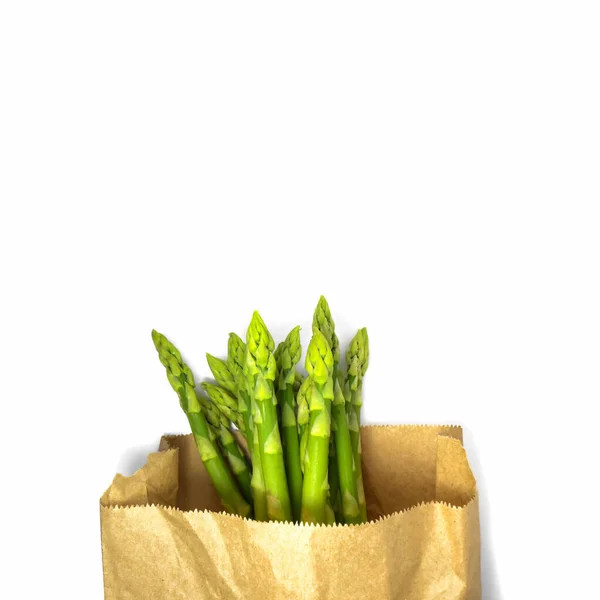 Surowe szparagi w papierowej torbie. Świeże zielone szparagi na białym tle — Zdjęcie stockowe