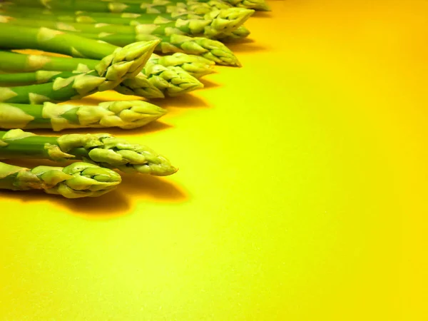 Surowe szparagi. Świeże zielone szparagi na żółtym tle. — Zdjęcie stockowe