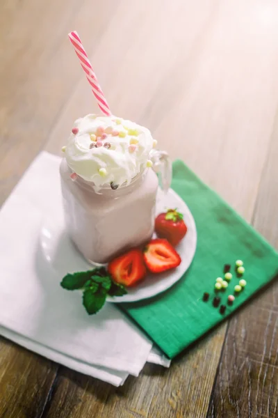 Glas mit hausgemachtem Erdbeer-Smoothie-Cocktail, serviert mit Schlagsahne, grüner Minze und frischen Beeren vor altem dunklen Holzhintergrund. Konzept der gesunden Ernährung. — Stockfoto