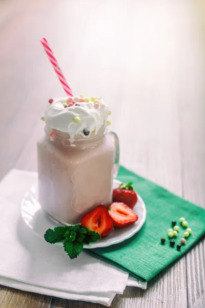 Pot en verre de cocktail smoothie aux fraises maison, servi avec crème fouettée, menthe verte et baies fraîches sur un vieux fond de bois sombre. Concept de saine alimentation . — Photo