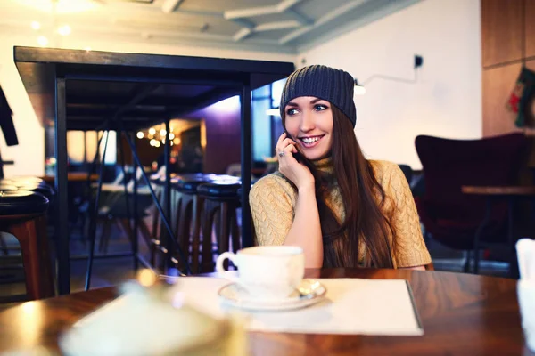 Retrato de menina bonita em chapéu usando seu telefone celular no café. Tonificado. Foco seletivo . — Fotografia de Stock