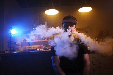 Bir mod tutarak Vaping adam. Vape dükkanında Buhar bulutu.