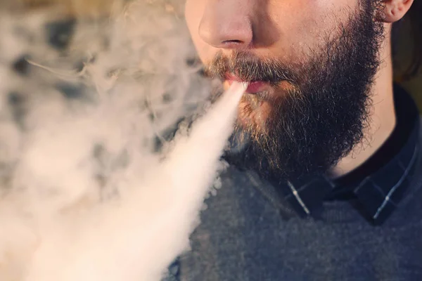 Uomini con la barba che vaporizzano e rilasciano una nuvola di vapore. primo piano . — Foto Stock